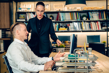 Senior attractive confident business working woman manager, mentor, boss with black formal suit discuss or comment with Caucasian man staff employee about sales and project in loft modern office