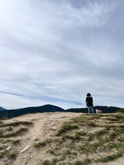 Fototapeta premium Woman observes the mountain landscape, with her dogs. Motivational concept.