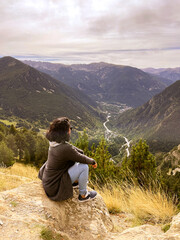Naklejka premium Woman sitting on top of a mountain observing the landscape. Motivational concept.