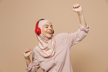 Young arabian asian muslim woman she wear abaya hijab pink clothes headphones listen to music dance...