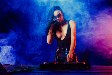 Sexy beautiful woman posing in headphones against abstract blue red background with smoke