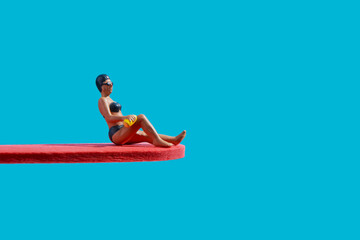 miniature woman sitting on a diving board