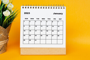 White January 2023 calendar with potted plant on yellow background.