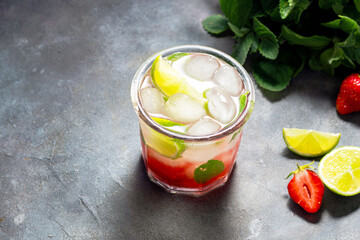 cold detox water with lime, strawberry, mint in the glass with ice cubes on gray background. copy space