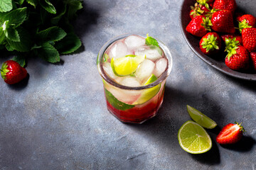 cold detox water with lime, strawberry, mint in the glass with ice cubes on gray background. copy space