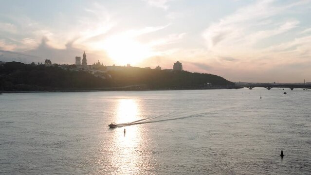Top Aerial view moving fishing boat ocean. evening sailing motor boat with angler on Dnipro river at sunrise sunset. landscape of bridge over lakes in Kiev Ukraine city. water transport, travel