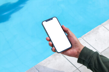 Mockup of a man browsing on to a white blank smartphone near a pool