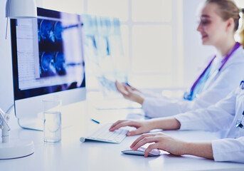 Two young female doctors working on computer at hospital.
