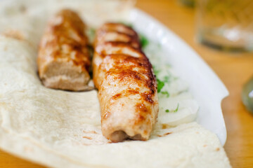 Appetizing grilled bavarian sausages or kebab on a pita with onion, parsley and dill.