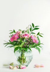 Beautiful summer flowers bouquet with roses and gerbera flower and green leaves in glass vase at...