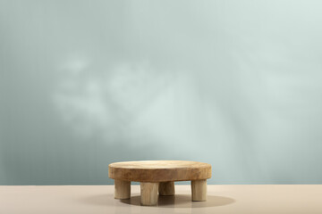 Empty round wooden podium for product presentation and leaves shadows on beige background for cosmetic product mockup