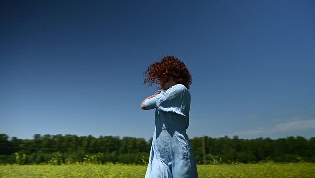 Caucasian young woman in a blue dress dances in a field. Video 360 degrees. 