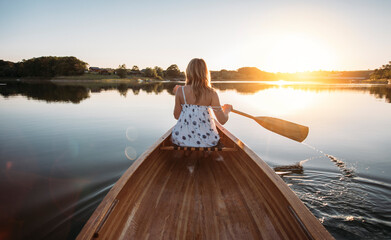 Fototapeta na wymiar Woman paddling the canoe on sunset lake 
