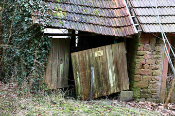 Altes Häuschen mit schief hängender Tür und schiefem Dach