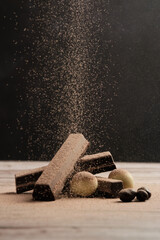 a set of different delicious chocolates, with chocolate sprinkled on a rustic wooden table....