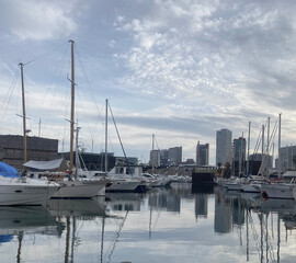 Marina port Forum Sant Adria, Barcelona, ​​Spain. Boats moored in the port. Reflection of buildings and boats in the water.