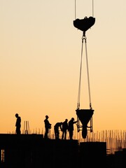 Builders pouring concrete with a crane at a construction site