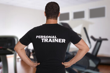 Professional personal trainer in gym, back view