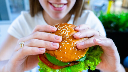 Vegan sandwich healthy vegetarian burger. Cute cheerful girl eating veggie hamburger with salad, avocado, vegetable. Vegetarian diet food concept.