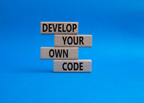 Develop your own code symbol. Concept words Develop your own code on wooden blocks. Beautiful blue background. Business and Develop your own code concept. Copy space.