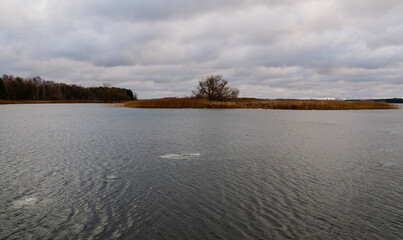 View of a small lake in autumn with a very cloudy sky.