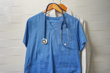 Closeup doctors scrus with stethoscope. Blue surgical smock with stethoscope on wooden hanger on...
