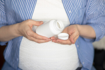 medicines for expectant mothers, a pregnant woman holds a jar of pills in her hands