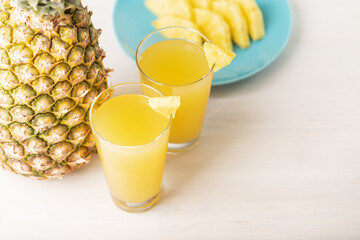 pineapple summer cocktail in glass and whole pineapple on white, fruity fresh juice with copy space