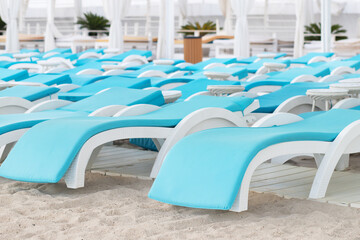 sun loungers on the sandy beach, white blue chairs by the sea