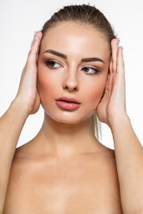 Closeup front image of a young woman with natural makeup, looking at the side, holding hands near face.