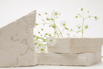 Empty stack of stones and flower platform podium on beige background. Minimal empty display product presentation scene.