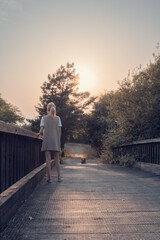 girl walking on wooden bridge. Tranquility at sunset.