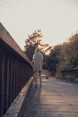 girl walking on wooden bridge. Tranquility at sunset.