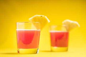 Pineapple juice in glass closeup near sliced fruit with spash and dripping liqid for summer vibes.