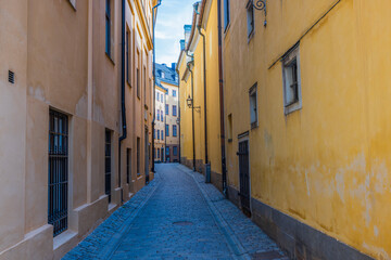 Beautiful view of narrow street between two yellow buildings. Sweden. Stockholm.