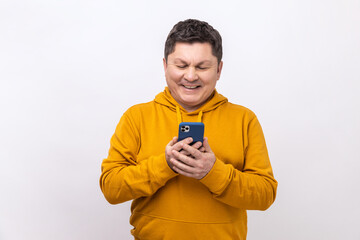 Attractive middle aged man using mobile phone with happy expression, addicted to smartphone,...