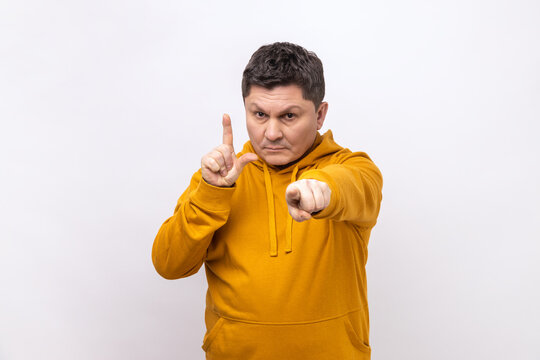 You are loser. Portrait of serious bossy man pointing at camera and showing lame or loser gesture, mocking your failures, wearing urban style hoodie. Indoor studio shot isolated on white background.
