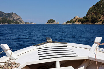 Obraz premium View from the bow of white wooden boat to Mediterranean sea with rock islands. Water travel, summer vacation