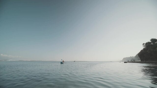 Indonesian Man Canoeing Paddling Canoe at Gunung Payung Beach, Bali, Indonesia Slow Motion