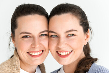 Two beautiful women twin sisters close-up face portrait, laying on floor