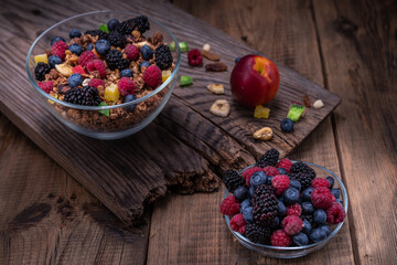 Various berries and granola. Mix of wild berries and granola. Still life of berries and nuts. Berries in a glass bowl.
