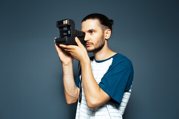 Studio portrait of young man photographer making photo with polaroid camera.