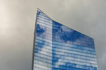 Mirrored office building windows with dramatic clouds background.