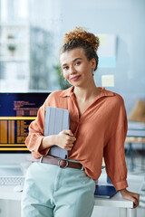 Portrait of young female IT specialist with digital tablet looking at camera standing at office