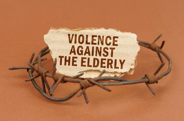 On a brown surface, barbed wire and a cardboard sign with the inscription - Violence against the...