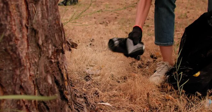 Volunteer woman with garbage bags cleaning forest. Plastic pollution and environmental problem concept.