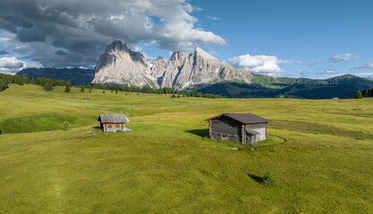Aerial view of Seiser Alm valley with traditional wooden mountain huts in Dolomites Italy . Morning drone shot of idyllic Alpe di Suisi blooming meadow in South Tyrol 
