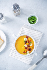Potato carrot soup with fried bacon slices in a bowl