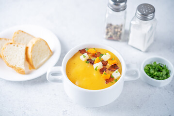 Potato carrot soup with fried bacon slices in a bowl