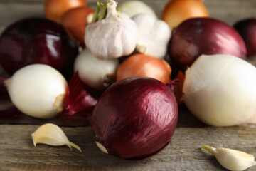 Fresh onion bulbs and garlic on wooden table, closeup